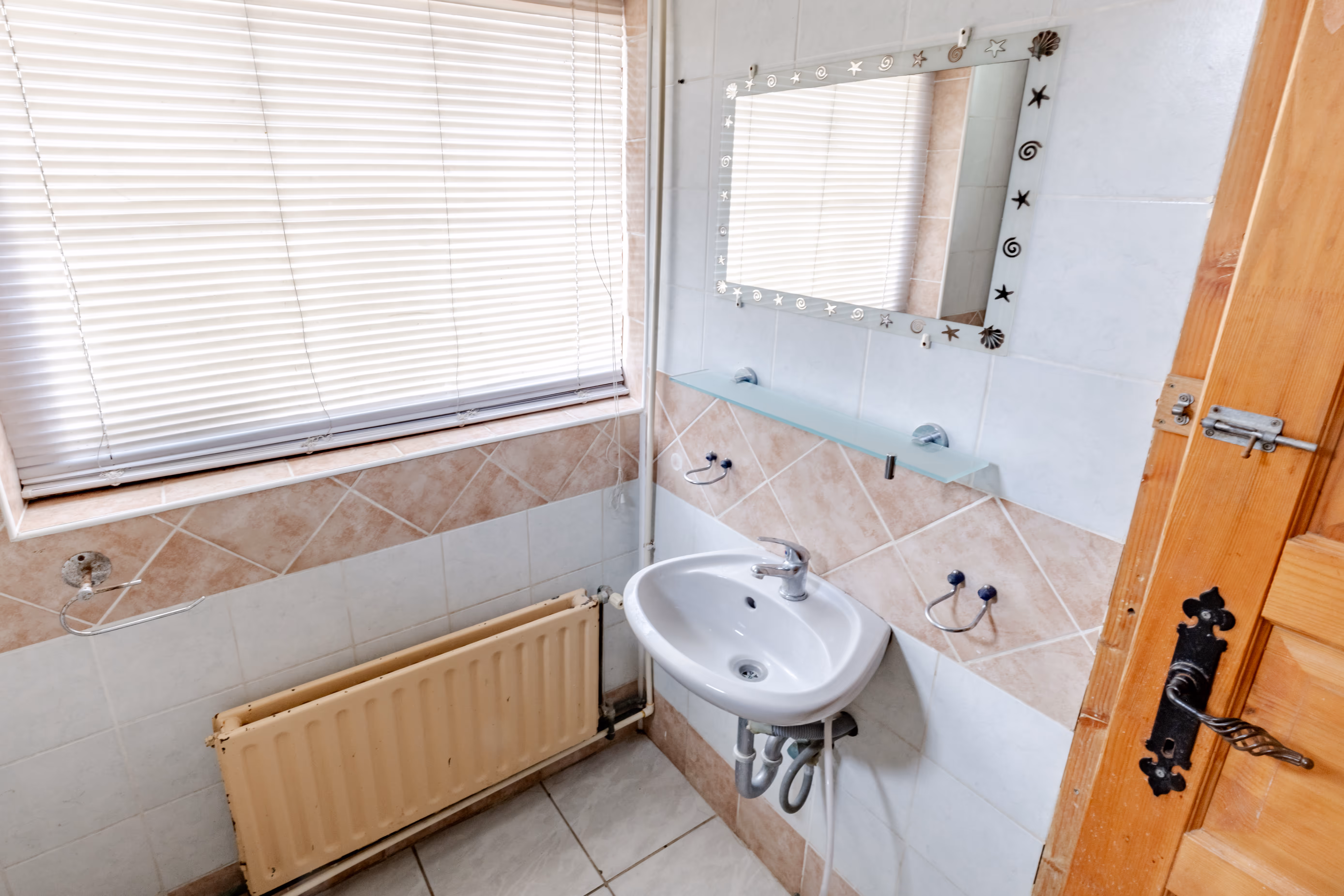 Fürdőszoba mosdóval, tükörrel, csempézett falakkal és ablakkal